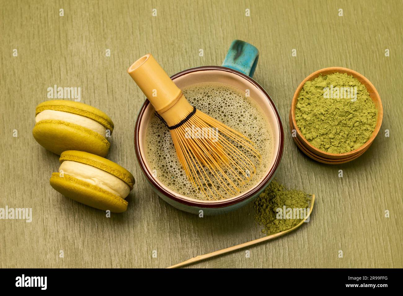 Biscuits au macaron vert. Fouet en bambou avec thé matcha. Poudre de matcha verte dans un bol en bois. Arrière-plan vert Banque D'Images