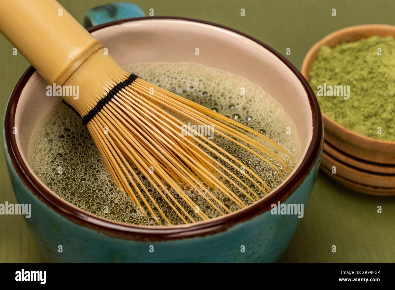 Fouet en bambou avec thé matcha. Poudre de matcha verte dans un bol. Thé Matcha dans un bol en bois. Arrière-plan vert Banque D'Images