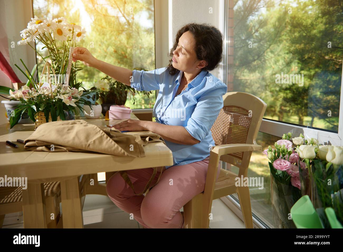 Femme enceinte travaillant arranger des fleurs, faisant une belle composition de fleurs dans un panier en osier à son propre magasin de fleurs Banque D'Images