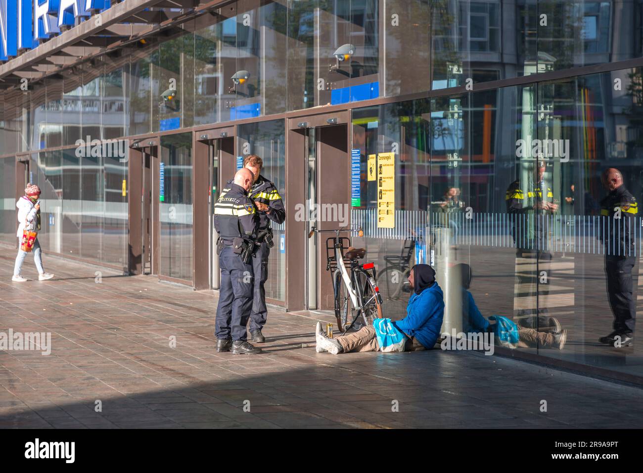 Rotterdam, pays-Bas - 9 octobre 2021: Policiers néerlandais enquêtant sur un homme sans domicile assis devant la gare centrale de Rotterdam, le Banque D'Images