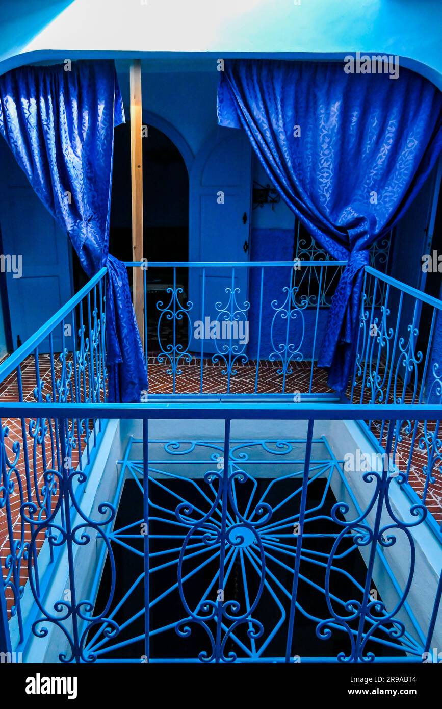 Centre de plusieurs balustrades métalliques au Riad Nerja à Chefchaouen, avec le thème traditionnel bleu répété trois étages drapés de soie bleue Banque D'Images