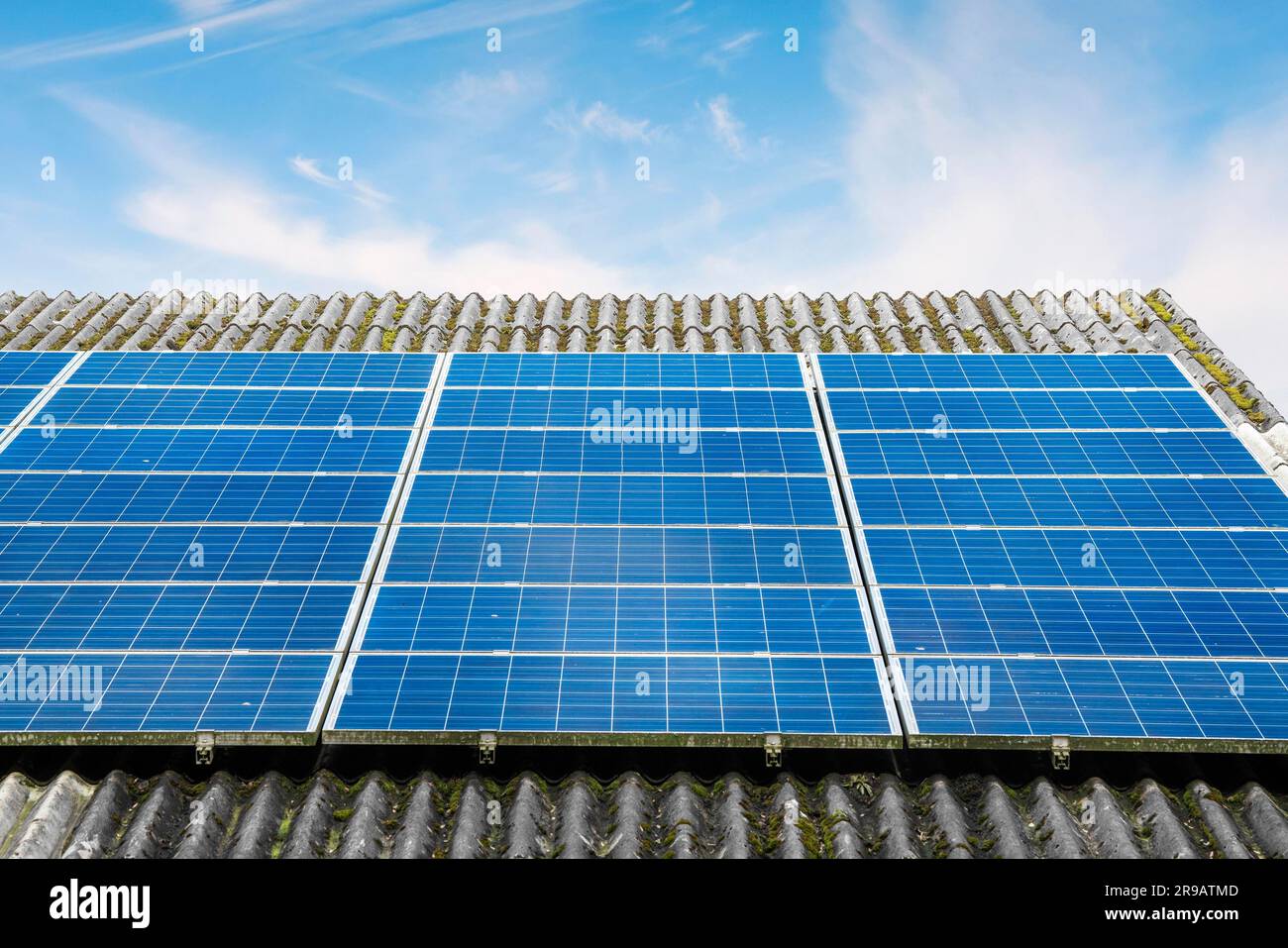 Panneaux solaires en bleu sur un toit dans des conditions de beau temps sous un ciel bleu Banque D'Images