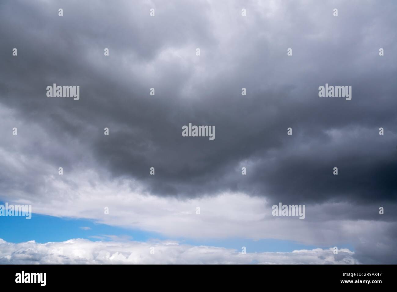 Nuages sombres avec pluie accrochée sur un ciel bleu vif lors d'une journée avec le temps changeant Banque D'Images