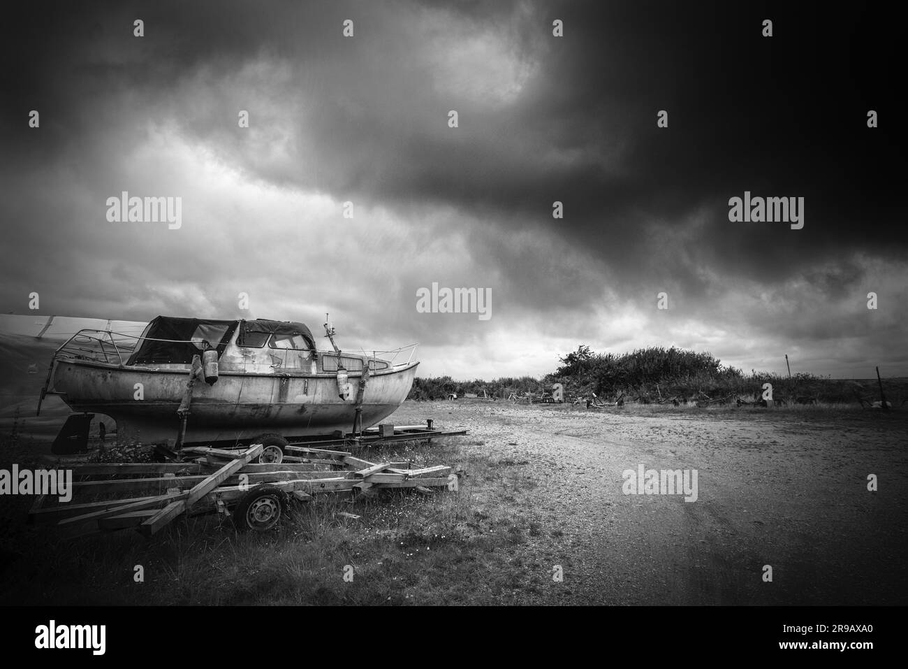 Bateau abandonné dans un mauvais état par temps nuageux dans tons noir et blanc monocrhome Banque D'Images