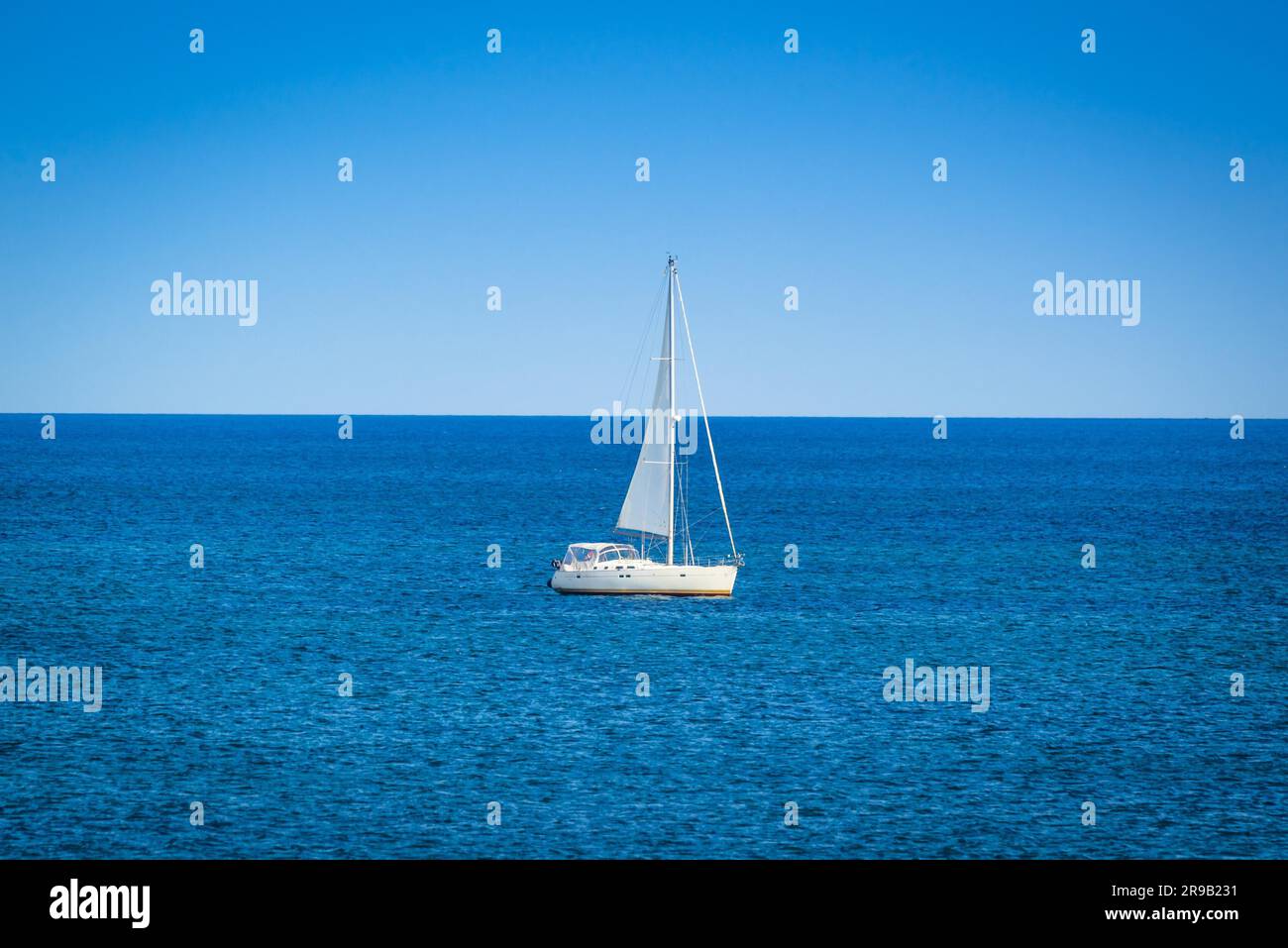 Petit voilier sur l'océan bleu à la lumière du jour Banque D'Images