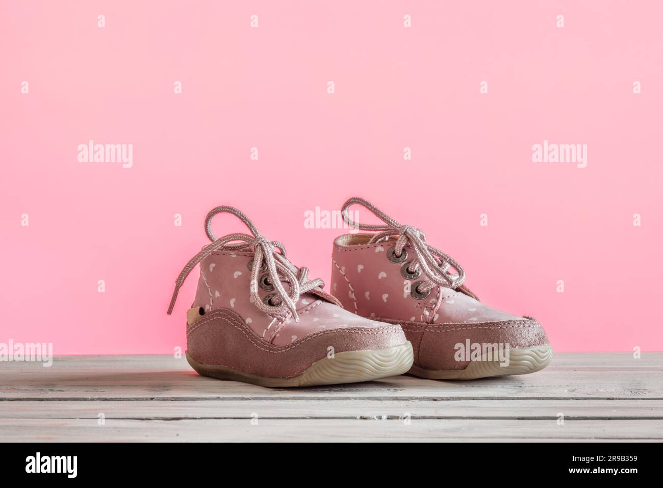 Les chaussons bébé en rose sur une table en bois Banque D'Images