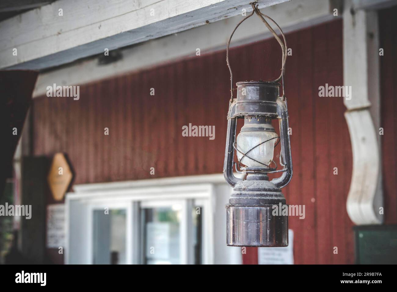 Vieille lampe à huile accrochée sur un porche à l'extérieur d'une maison rouge dans un style ancien Banque D'Images