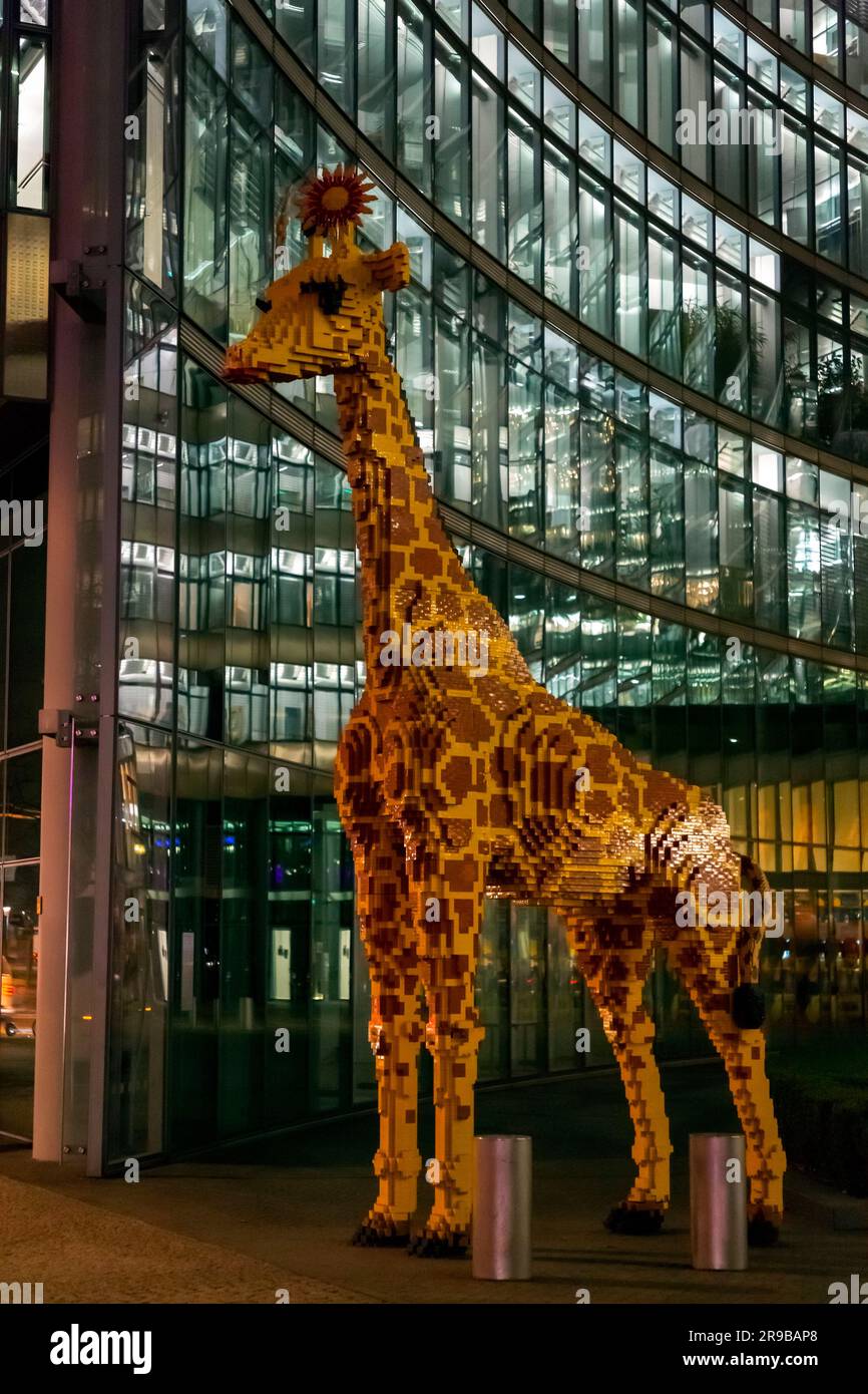 Berlin, Allemagne - 17 décembre 2021 : immense statue de girafe en plastique en face du centre de découverte de Legoland, prise de vue de nuit à Berlin, Allemagne. Banque D'Images
