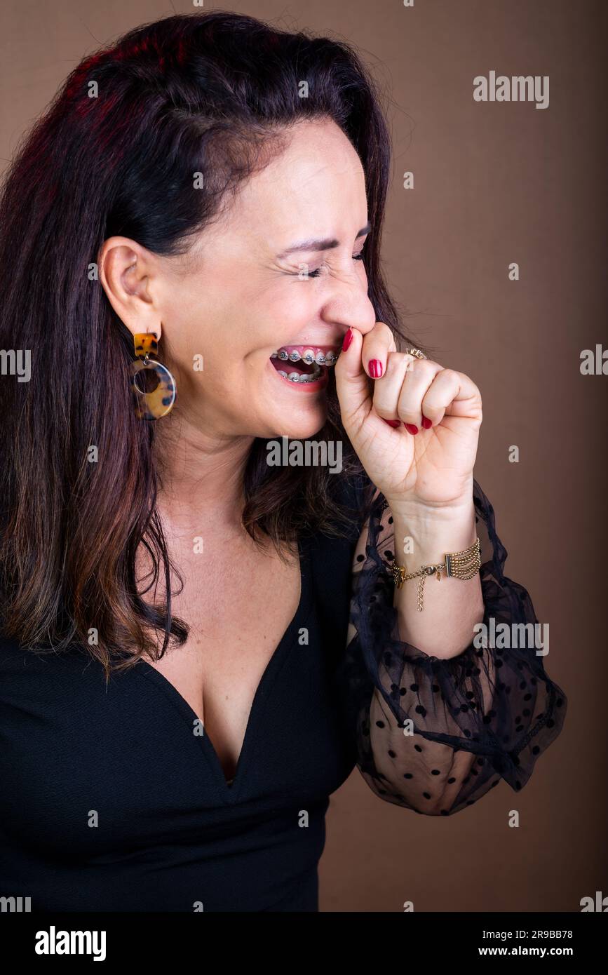 Portrait d'une femme entraînante, heureuse, avec ses mains sur son visage et ses yeux fermés. Gestion de la motivation. Isolé sur fond marron. Banque D'Images