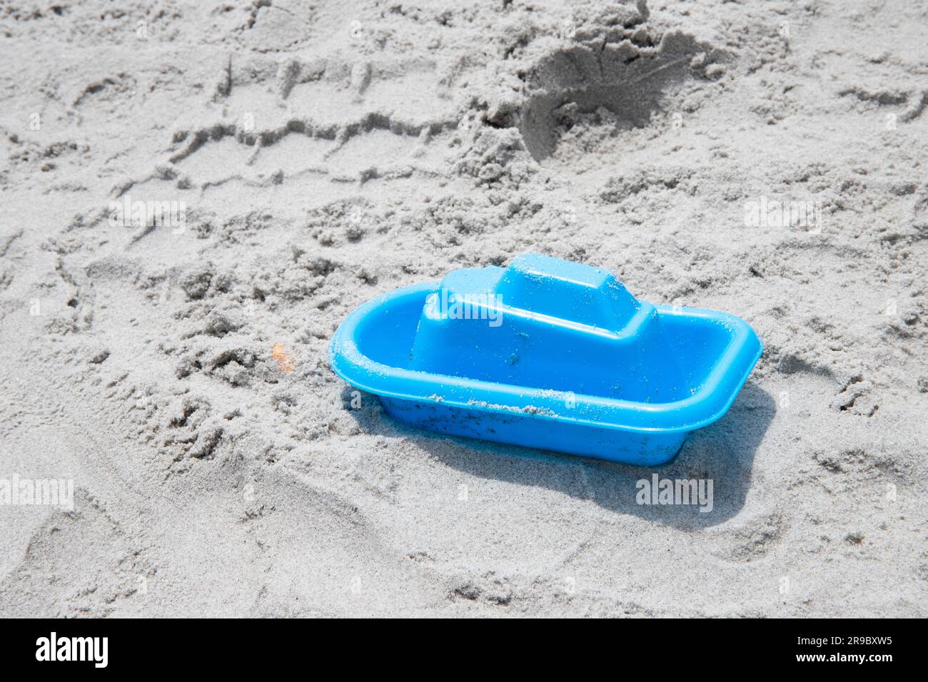 bateau à jouets bleu abandonné sur le sable à la plage, ne jouant pas avec, copier l'espace Banque D'Images