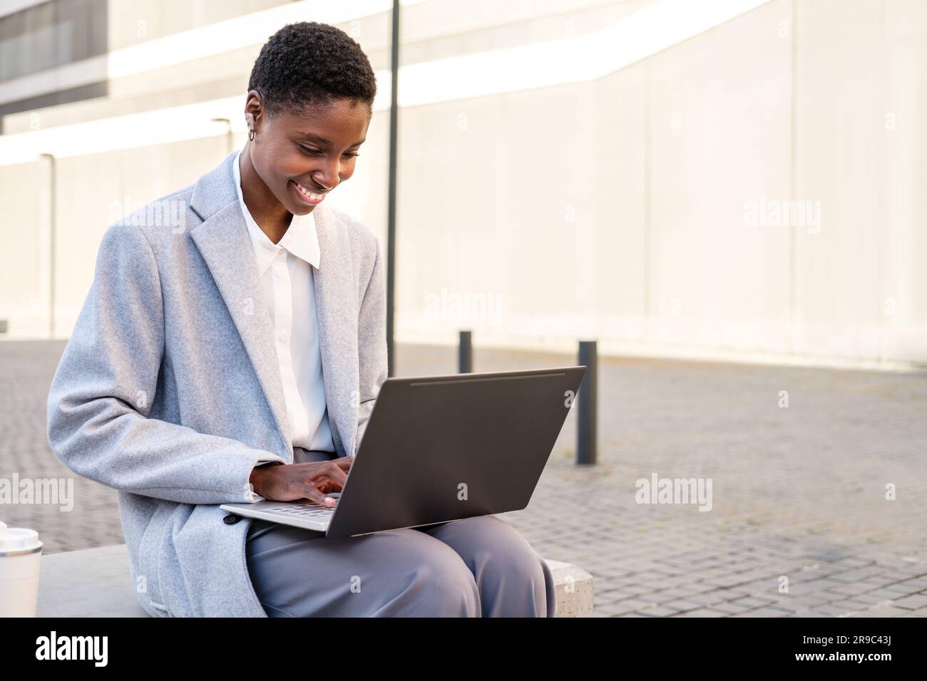 portrait horizontal d'une jeune femme africaine élégante. Elle est assise près du tribunal et utilise un ordinateur portable Banque D'Images