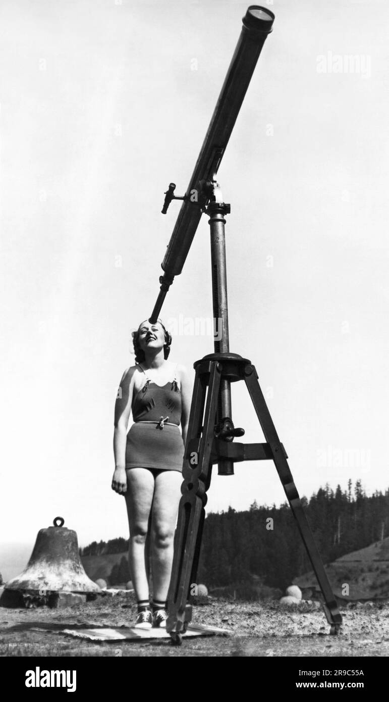 Cape Foulweather, Oregon : c. 1935 Une jeune femme regardant à travers un télescope. Banque D'Images