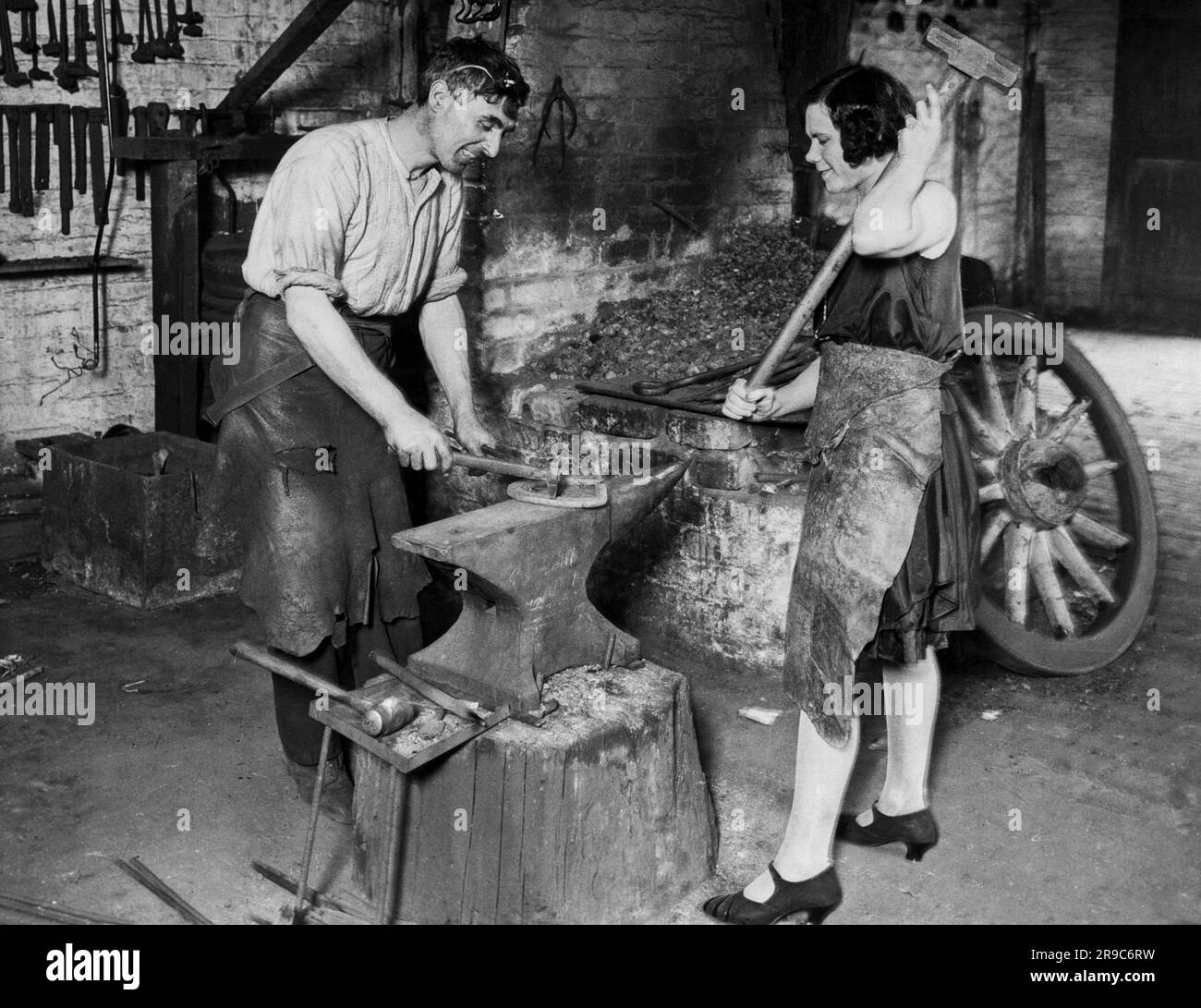 Wolverhampton, Angleterre: 1930 Une femme au travail comme attaquant avec son mari dans leur atelier de forgeron. Banque D'Images