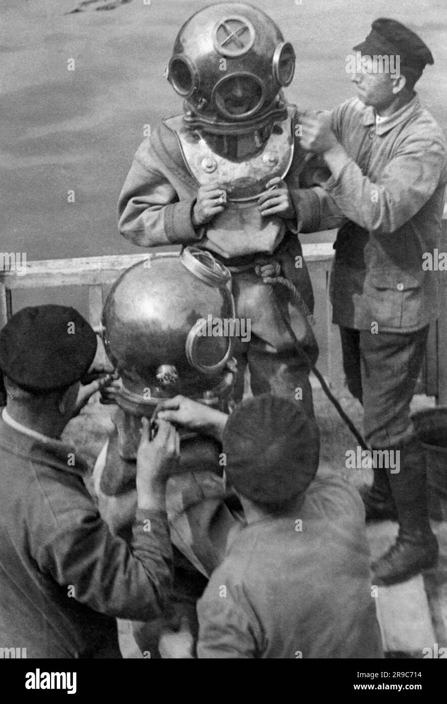 Berlin, Allemagne: c. 1932 le photographe et photojopurnaliste Willie Ruge et son partenaire se préparent à prendre les premières photos sous-marines à l'extérieur d'une cloche de plongée. Leurs chaussures pèsent 36 livres et l'équipement combiné pour cette entreprise sous la surface de la rivière Elbe pesait à 320 livres. Ici, les derniers ajustements sont faits à leurs combinaisons de plongée. Banque D'Images