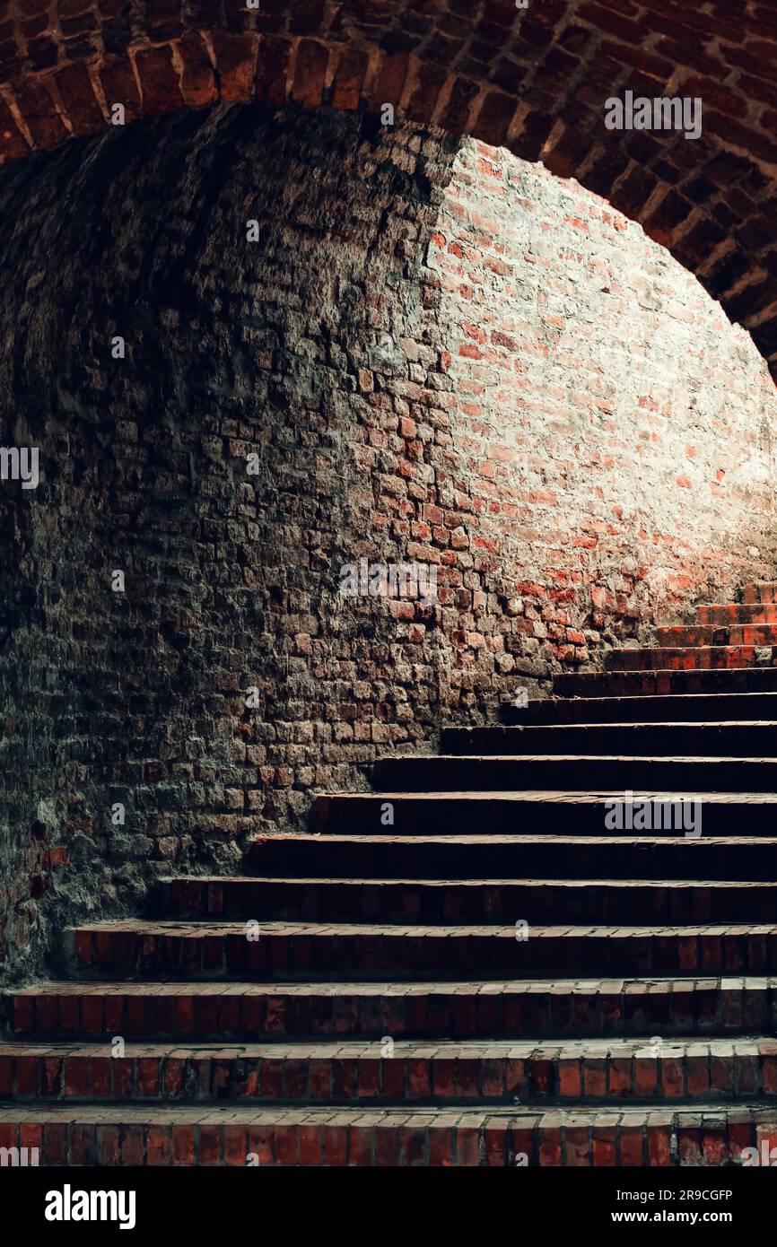Passage en briques vintage avec escalier menant à la sortie lumineuse, mise au point sélective Banque D'Images