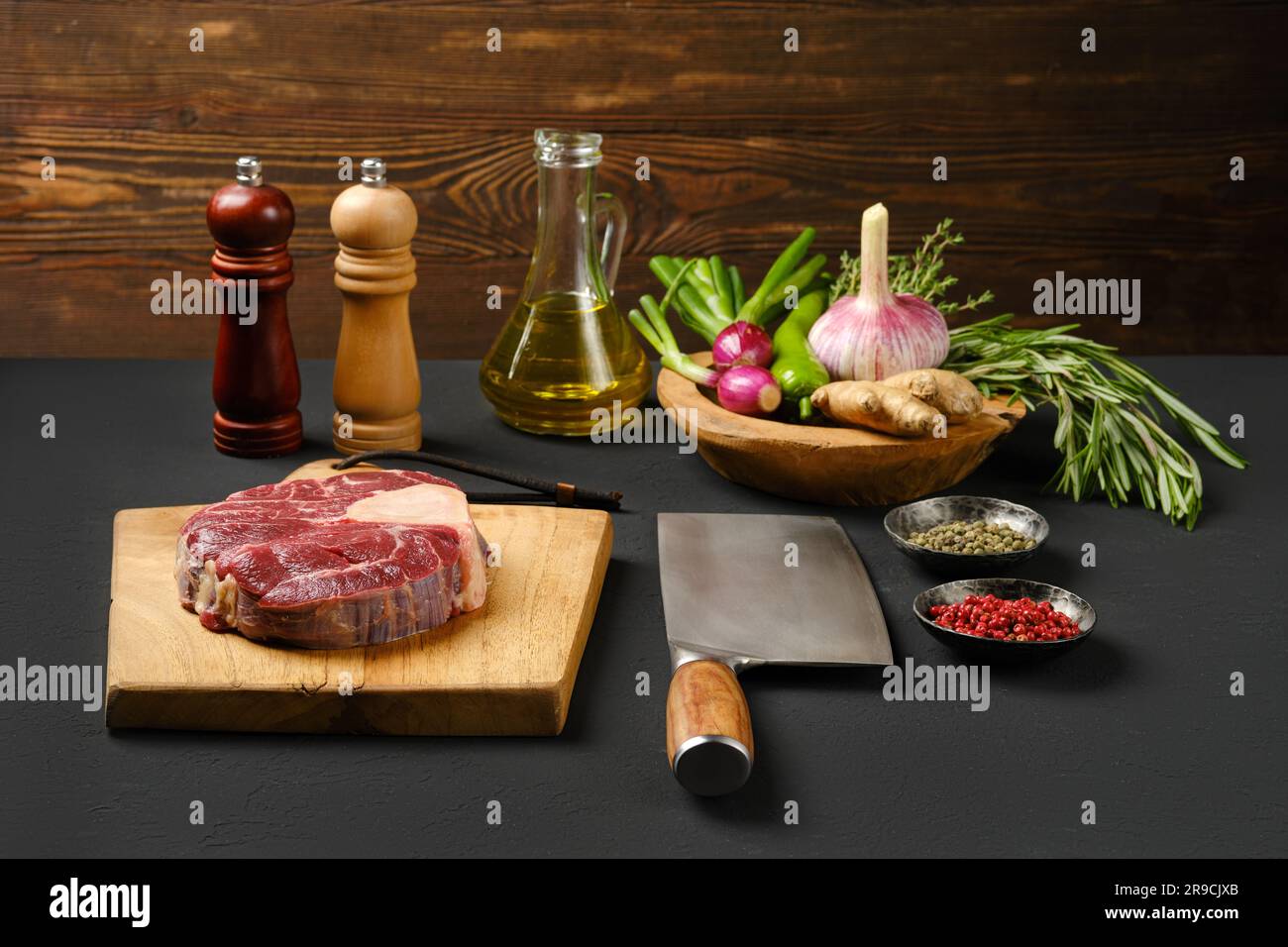 Coupe transversale de la tige de bœuf crue sur la planche à découper avec les ingrédients pour la cuisson Banque D'Images