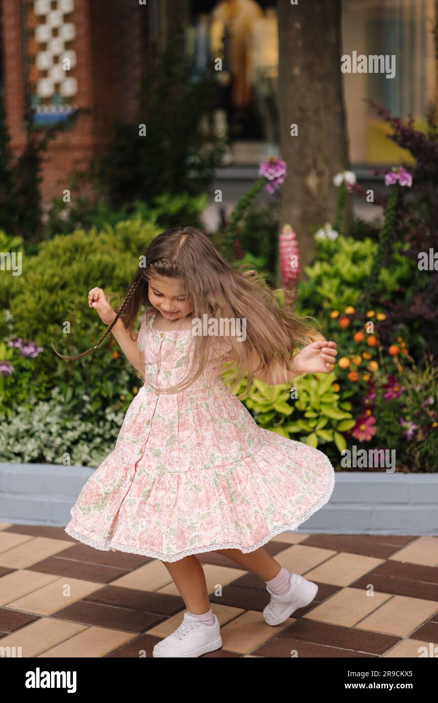 Adorable petite fille dans la robe magnifique tour autour. Un enfant heureux qui marche dans un centre commercial ouvert Banque D'Images