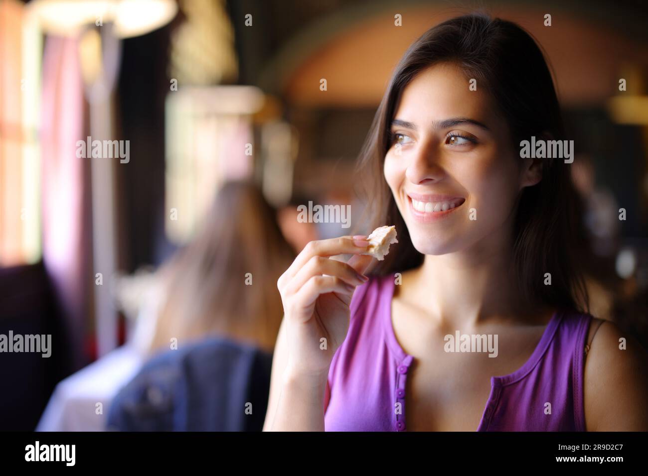 Bonne femme mangeant du pain dans un restaurant qui donne sur le côté Banque D'Images