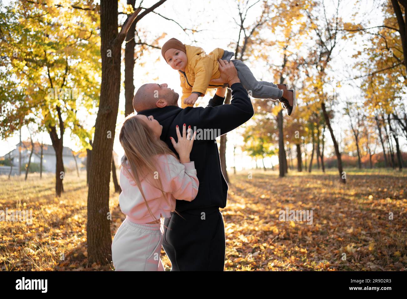 Famille jouant dans le parc d'automne en s'amusant. Bonne mère père et bébé garçon sur la promenade automnale dans la forêt Banque D'Images