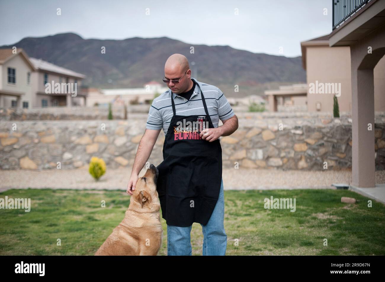 L'ancien combattant de la guerre d'Irak se détend avec son chien tout en cuisinant. Banque D'Images