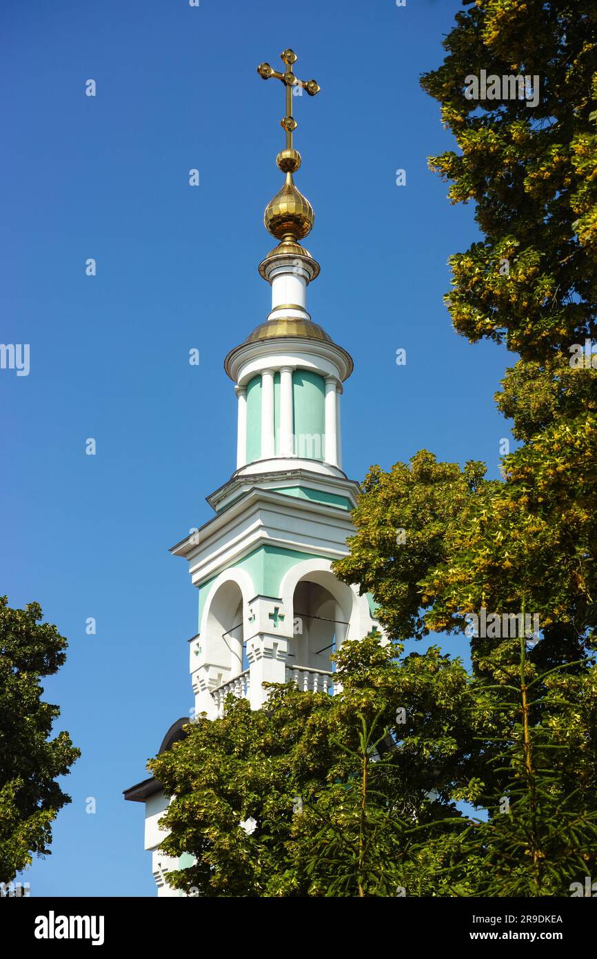 Un clocher de l'église orthodoxe derrière des tilleuls contre un ciel bleu Banque D'Images