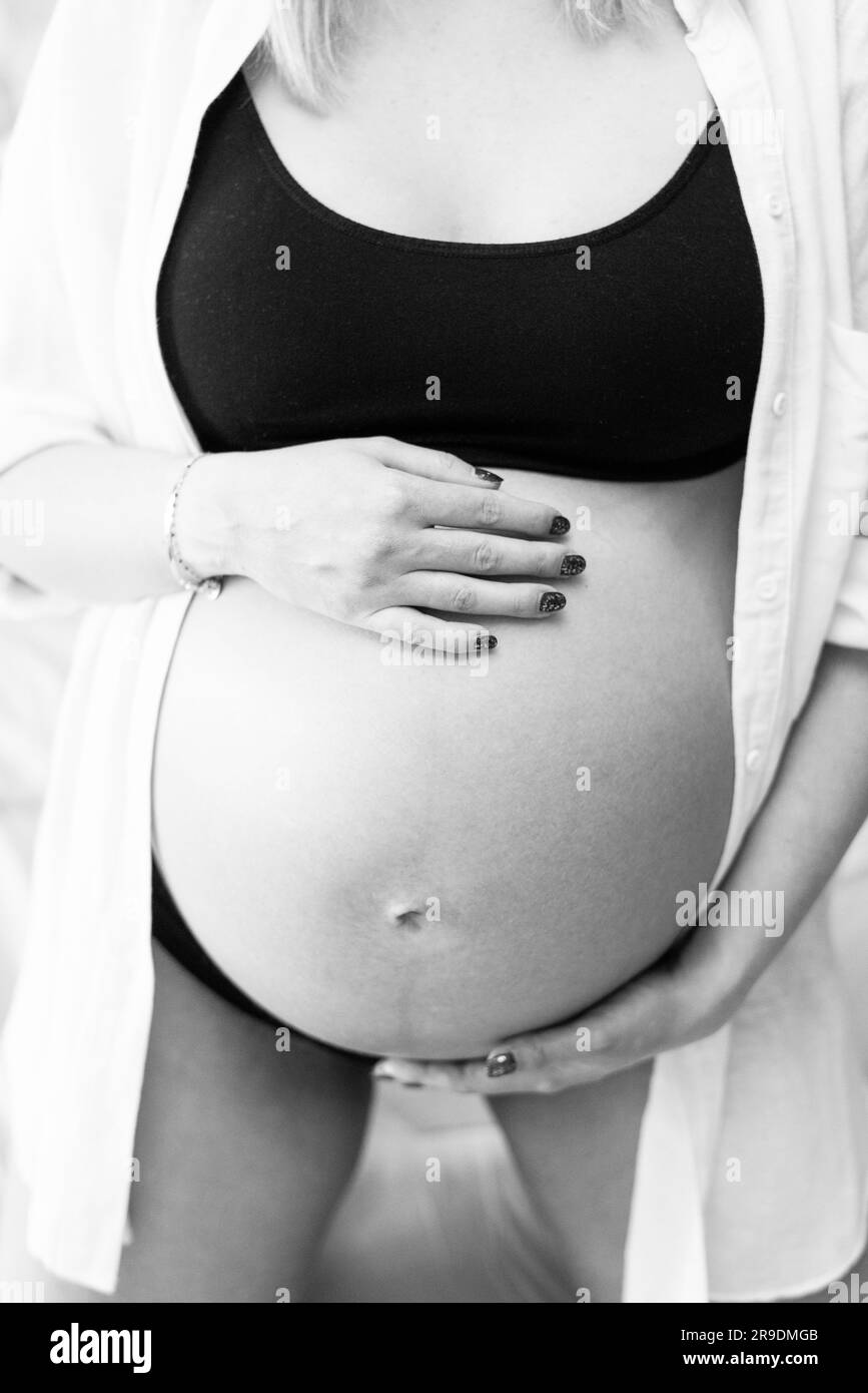 Jeune femme enceinte dans un studio d'éclairage célébrant son premier enfant Banque D'Images