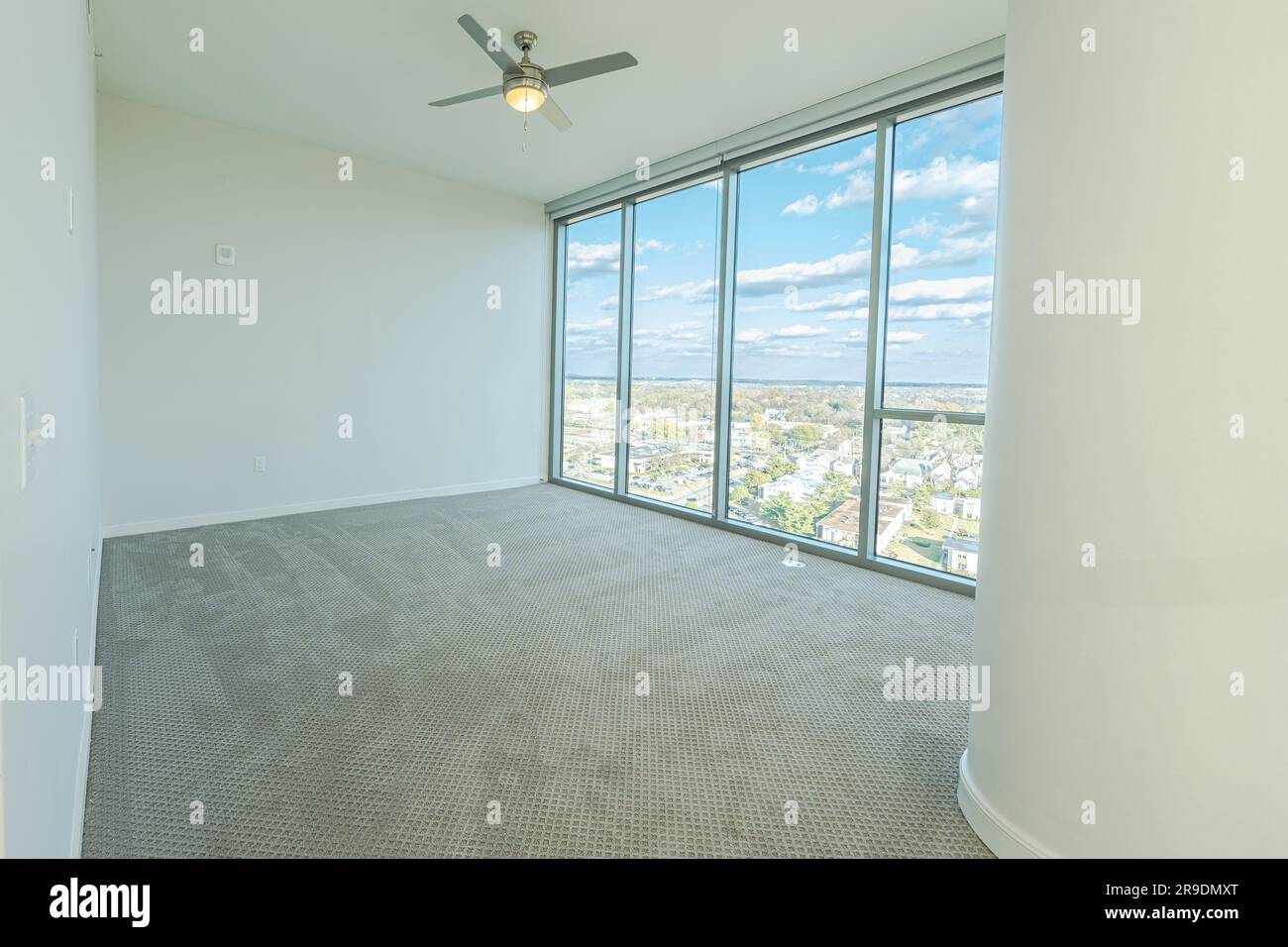 Un intérieur spacieux et spacieux avec un ventilateur de plafond et de grandes fenêtres offrant une vue spectaculaire Banque D'Images