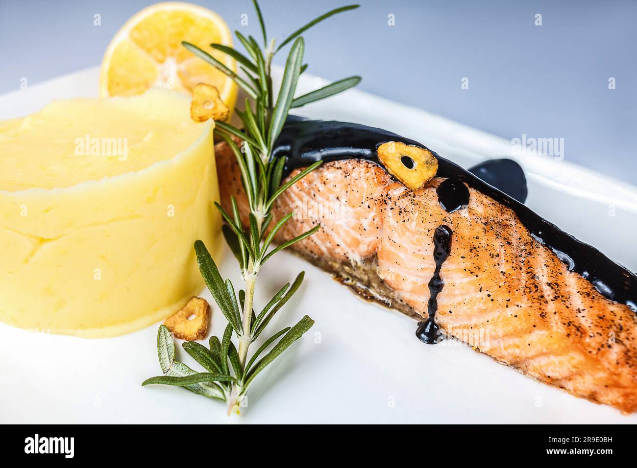 Une assiette de saumon fraîchement frit, servie avec une sauce aux herbes et au chocolat maison pour un délicieux plat de fruits de mer sain. Banque D'Images