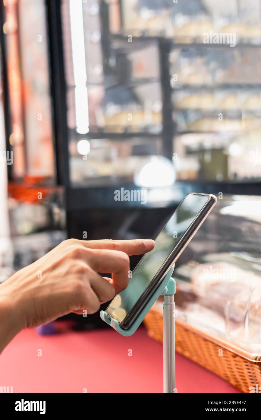 Propriétaire de petite entreprise utilisant le téléphone mobile vérifier la commande commerciale en ligne. Banque D'Images