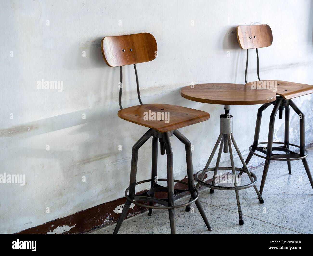 Chaises anciennes vides, dossier, siège et table ronde sur le côté, décorée sur fond de mur blanc ancien, intérieur de style loft. Swive Banque D'Images