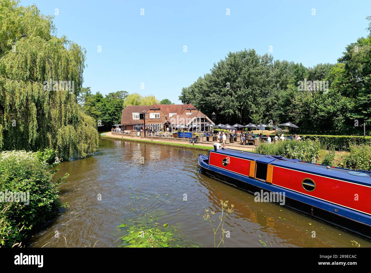 Un bateau étroit passant devant le pub Anchor par Pyrford écluse sur le canal de navigation de River Wey lors d'un chaud jour d'été Surrey Angleterre Royaume-Uni Banque D'Images