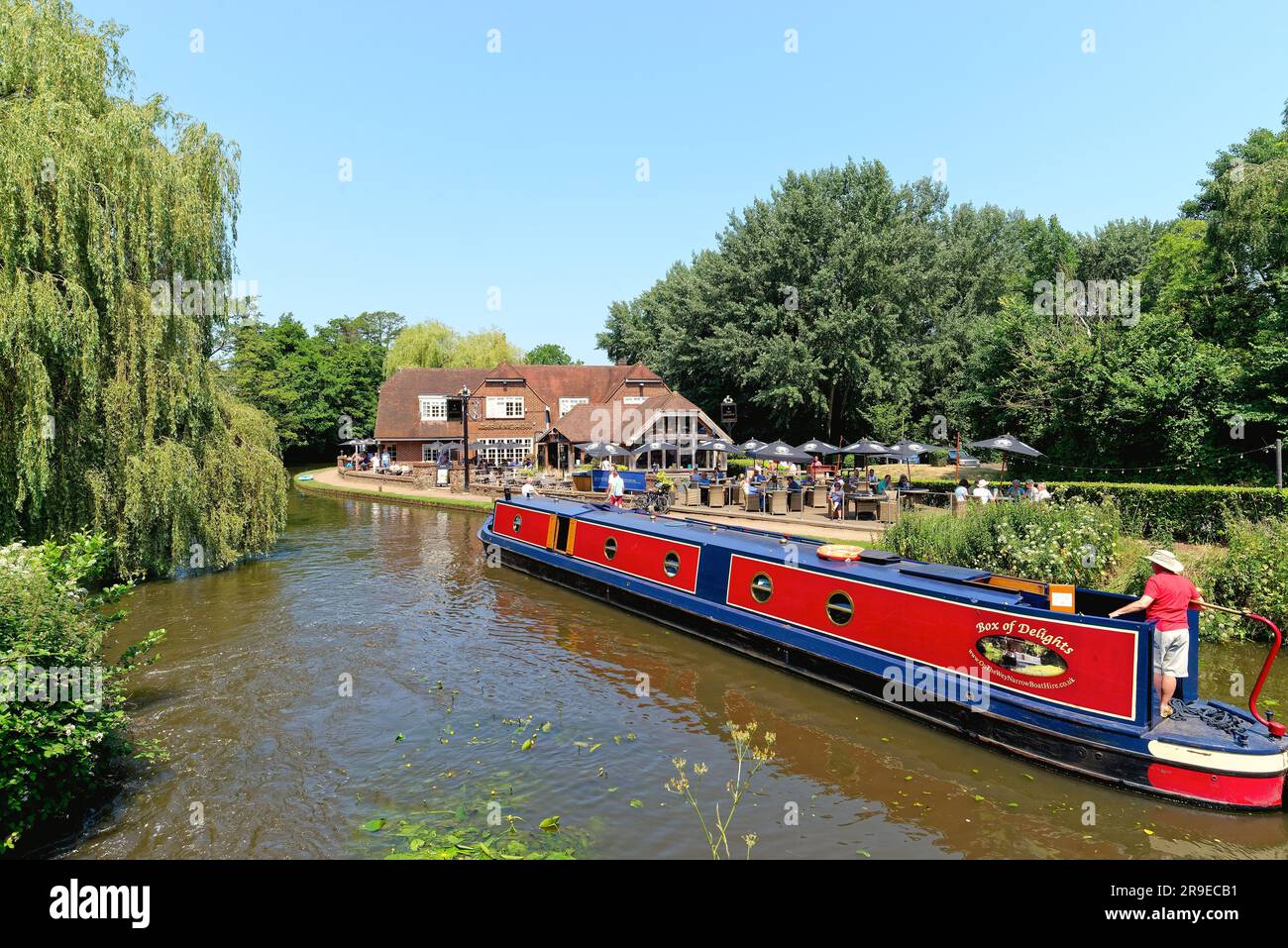 Un bateau étroit passant devant le pub Anchor par Pyrford écluse sur le canal de navigation de River Wey lors d'un chaud jour d'été Surrey Angleterre Royaume-Uni Banque D'Images