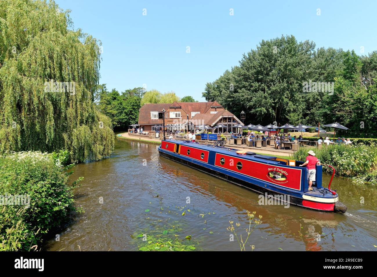 Un bateau étroit passant devant le pub Anchor par Pyrford écluse sur le canal de navigation de River Wey lors d'un chaud jour d'été Surrey Angleterre Royaume-Uni Banque D'Images