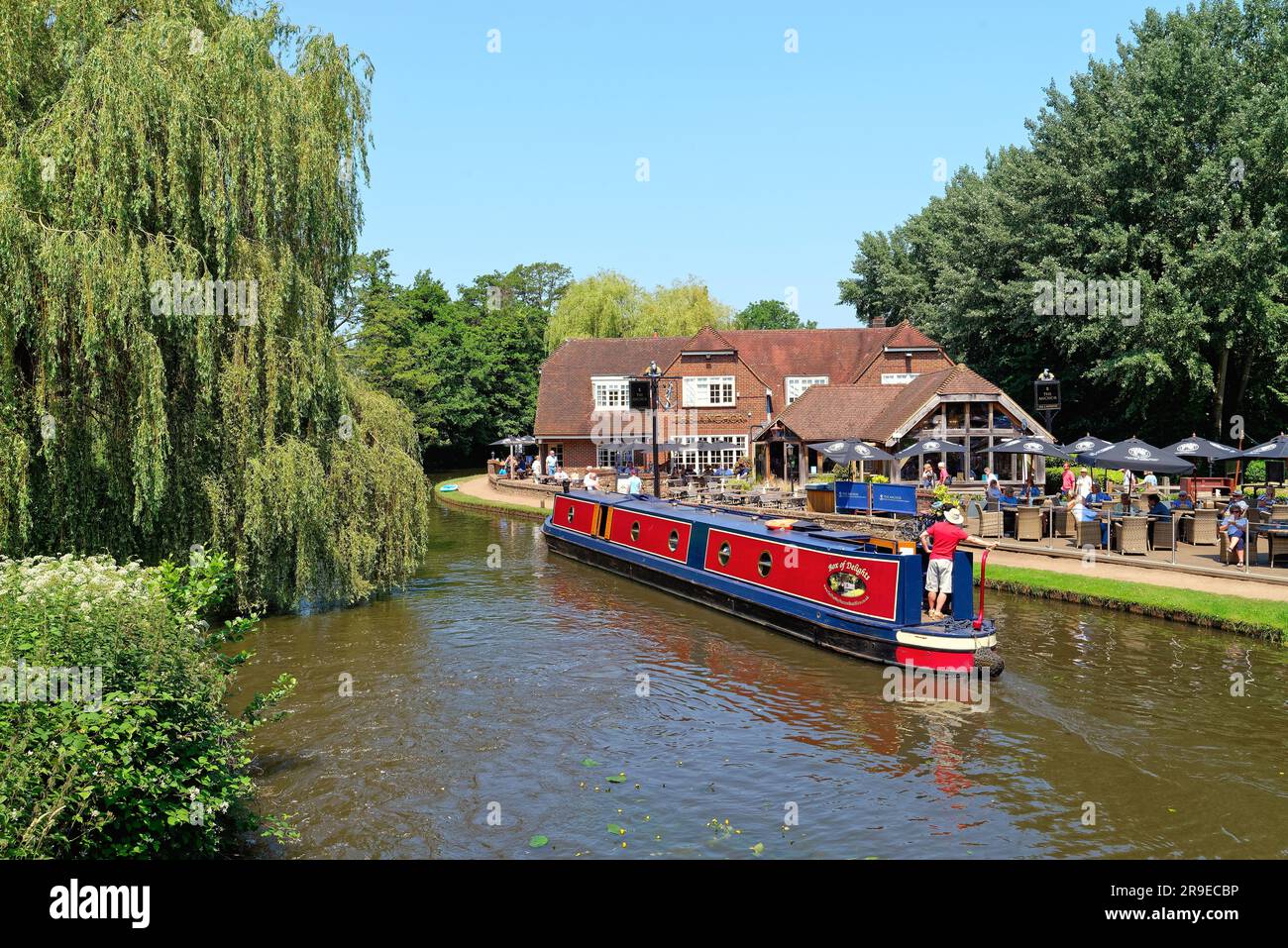 Un bateau étroit passant devant le pub Anchor par Pyrford écluse sur le canal de navigation de River Wey lors d'un chaud jour d'été Surrey Angleterre Royaume-Uni Banque D'Images