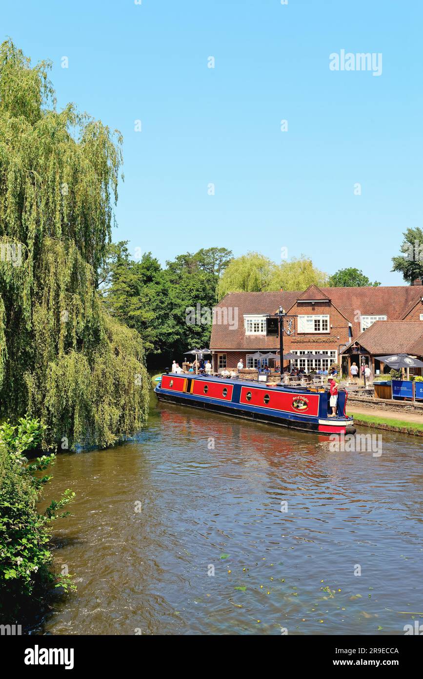 Un bateau étroit passant devant le pub Anchor par Pyrford écluse sur le canal de navigation de River Wey lors d'un chaud jour d'été Surrey Angleterre Royaume-Uni Banque D'Images