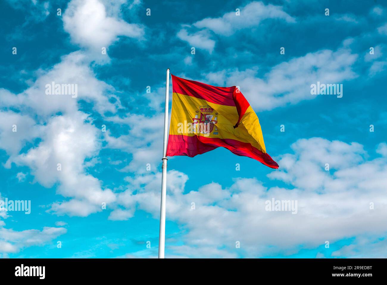Drapeau espagnol agitant dans le ciel bleu clair. Banque D'Images