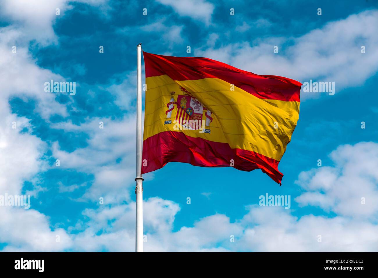 Drapeau espagnol agitant dans le ciel bleu clair. Banque D'Images
