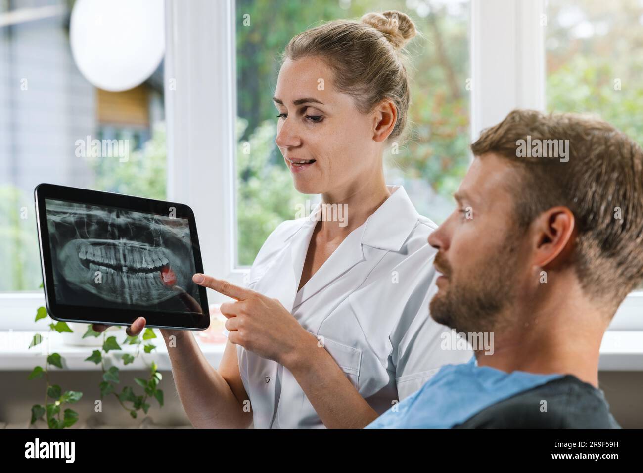 dentiste montrant et expliquant à son patient une photo de radiographie dentaire avec une dent de sagesse affectée Banque D'Images