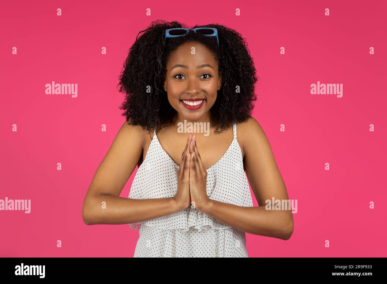 Souriante excitée jeune femme noire du millénaire étudiant faisant le geste de prière, se réjouir, merci et demander Banque D'Images