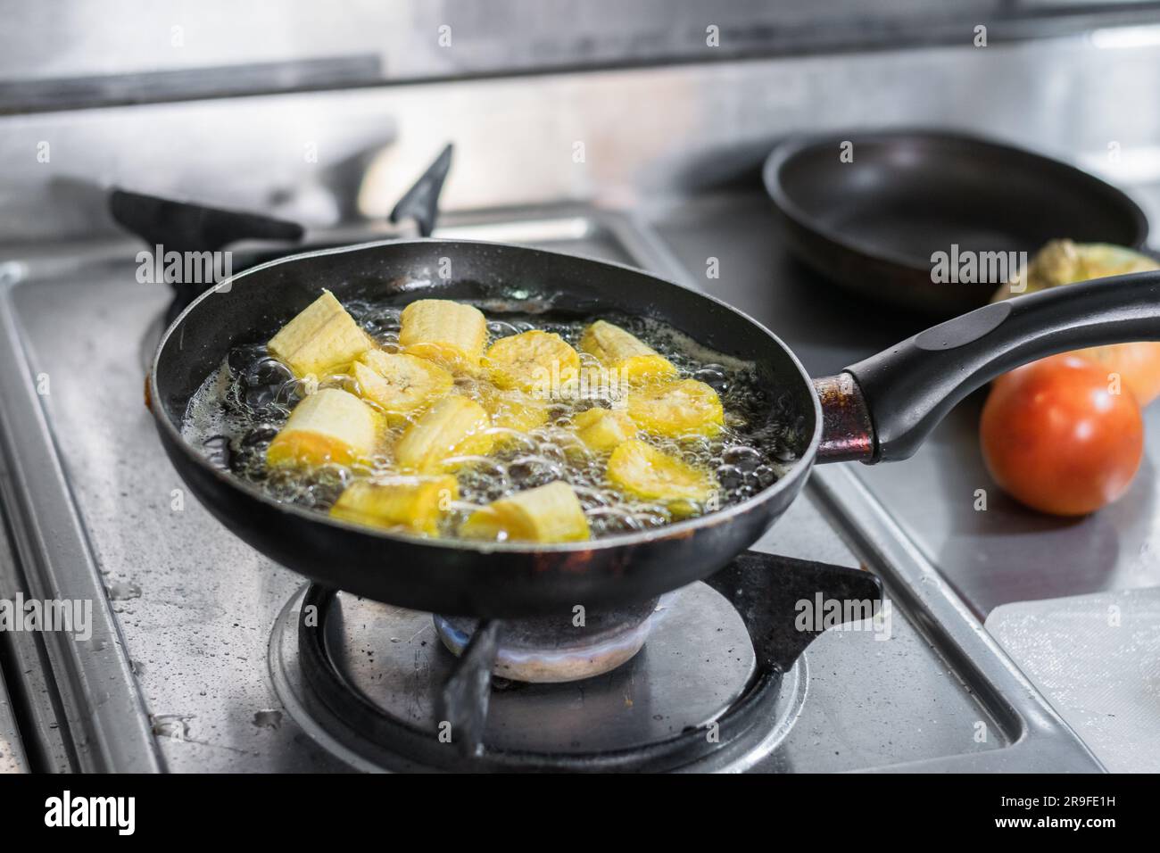 gros plan d'une poêle dans laquelle les plantains verts sont frits en morceaux pour faire des patacones. Banque D'Images