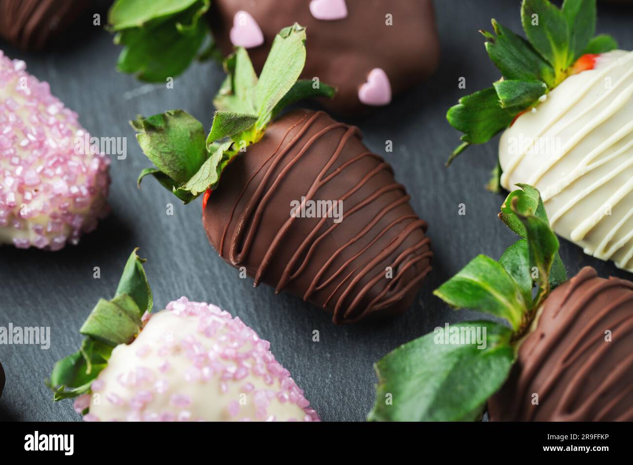 Fraises gourmandes enrobées de chocolat sur fond sombre. Banque D'Images