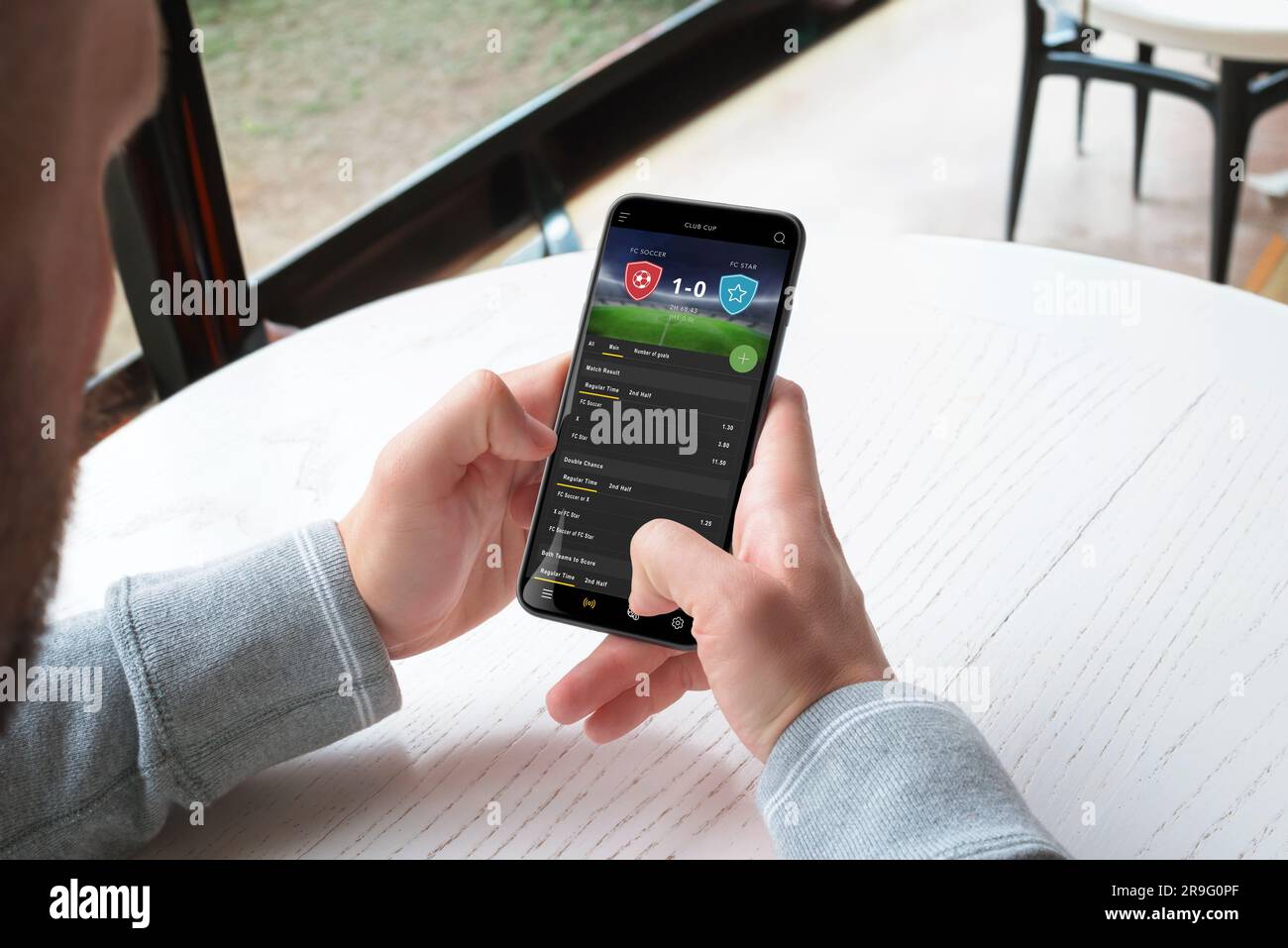 L'homme parie en direct sur un match de football grâce à une application pour téléphone portable. Le concept de Paris sportifs en ligne. Une application moderne pour plates-formes mobiles Banque D'Images