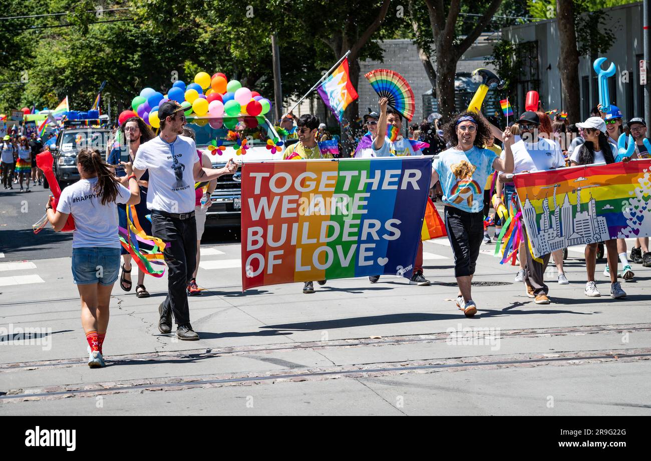 Un groupe de la société de plein air REI tient un panneau arc-en-ciel qui dit « ensemble, nous sommes les bâtisseurs de l'amour » dans le cadre de l'événement annuel Pride Parade. Banque D'Images