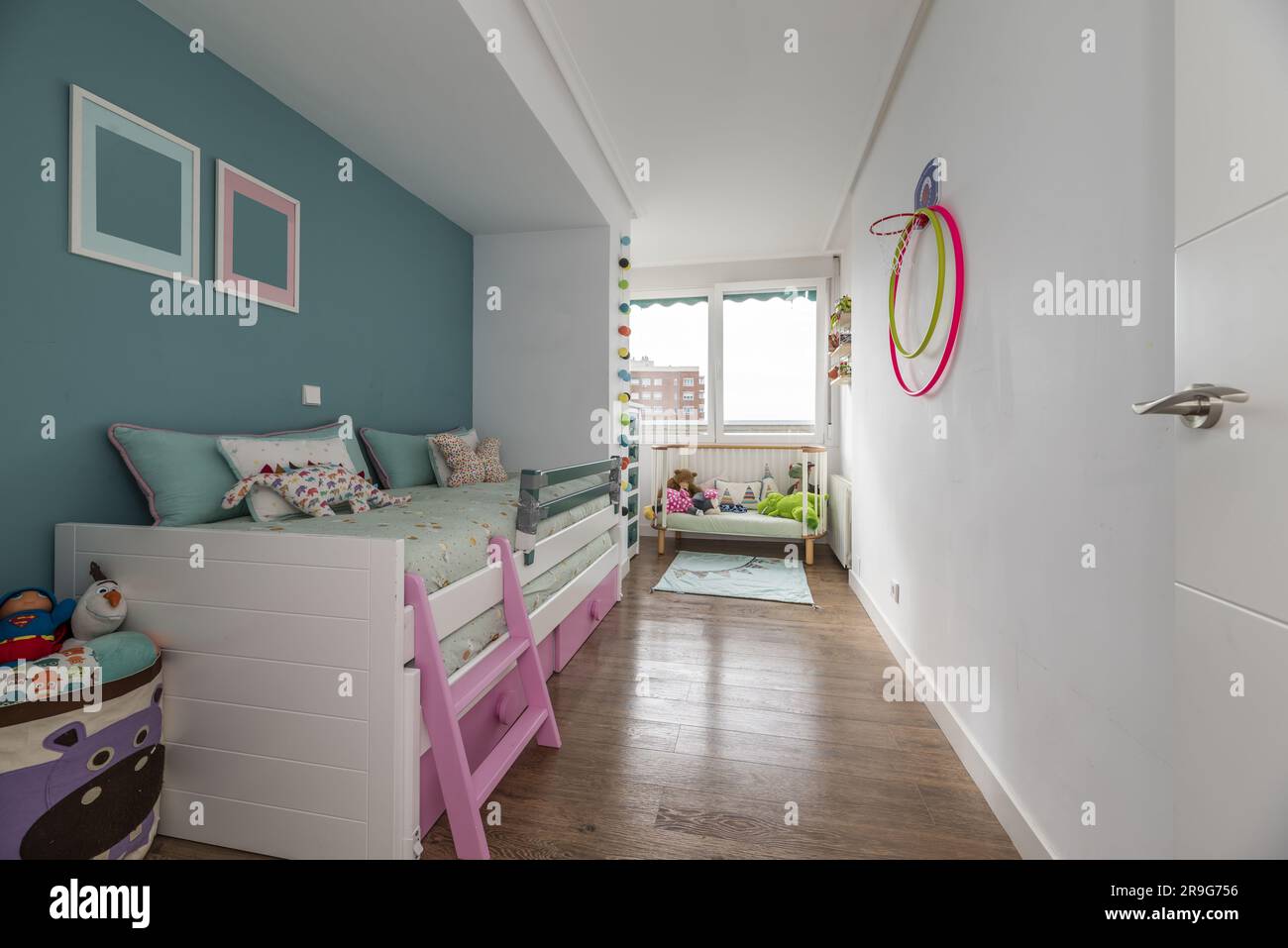 Chambre jeune avec lit en bois blanc avec deux matelas roses, commode et murs peints en deux tons Banque D'Images