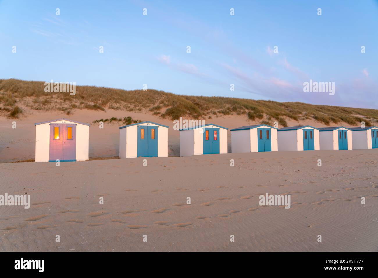 Au bord de la mer, il y a une rangée de cabanes de plage côte à côte, où le soleil se couche Banque D'Images