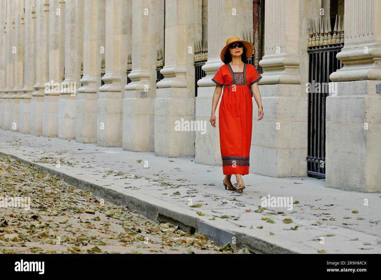 Marcher à travers le Palais Royal portant une robe paysanne brodée rouge, une femme asiatique mature glamour à Paris Banque D'Images