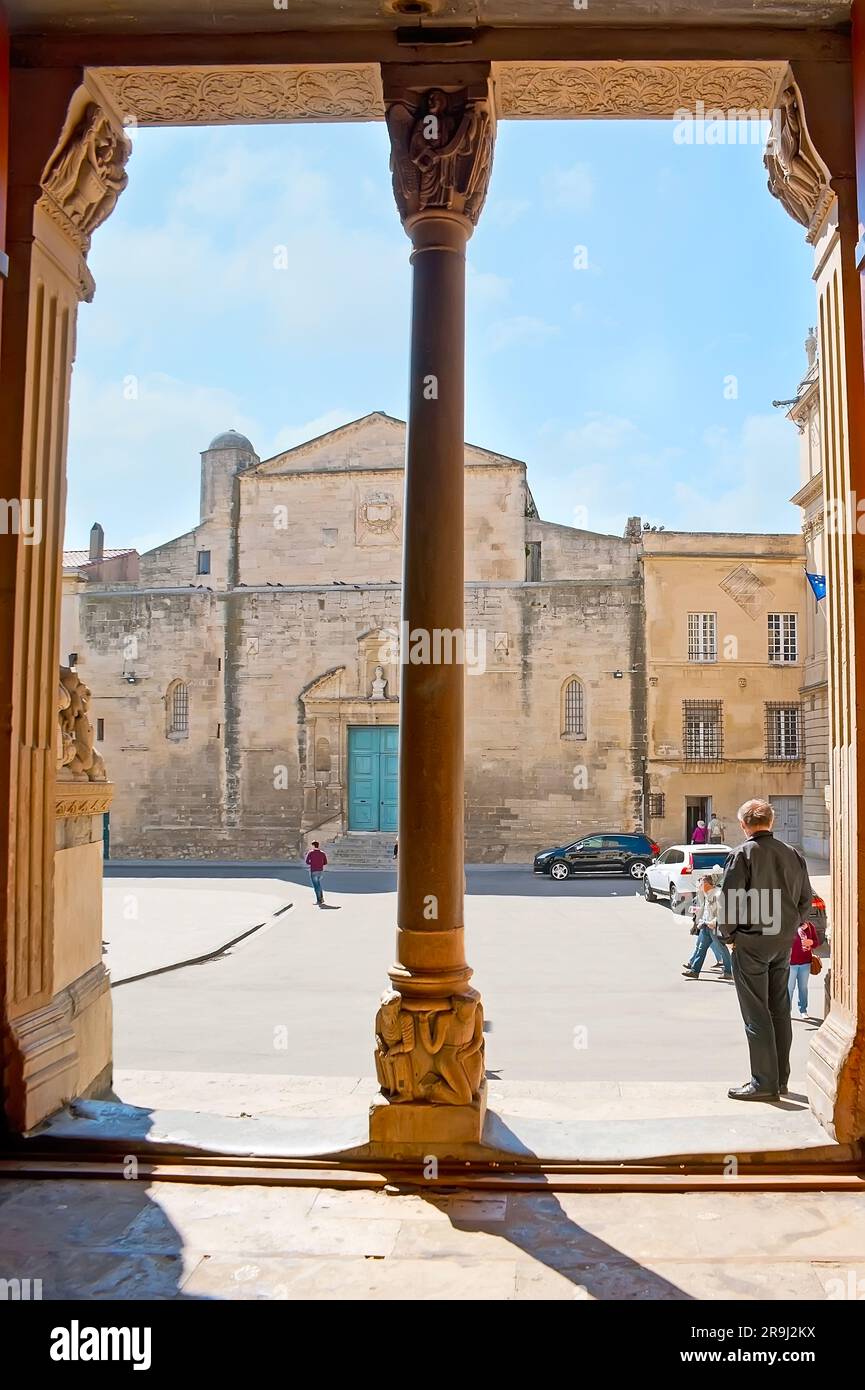 Vue sur la place de la République et l'église Sainte-Anne à travers la colonne sculptée médiévale de la cathédrale Saint-Trophime, Arles, France Banque D'Images