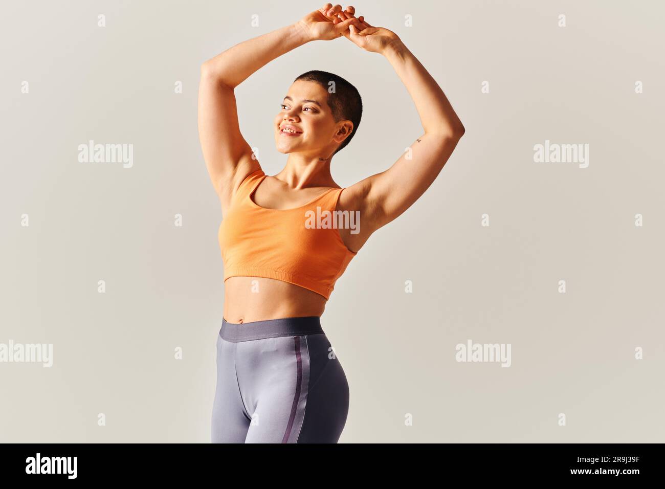 formes du corps, femme gaie et à poil court qui s'étire sur fond gris, modèle de forme physique ajusté, athlétique et confiant, autonomisation, motivation, travail Banque D'Images