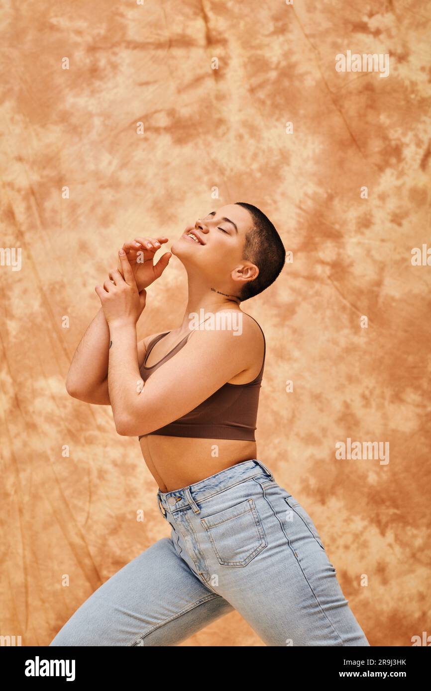 denim mode, gen z, heureuse femme curvy avec tatouage posant sur fond beige marbré, mouvement de positivité du corps, estime de soi, confiance, cheveux courts Banque D'Images
