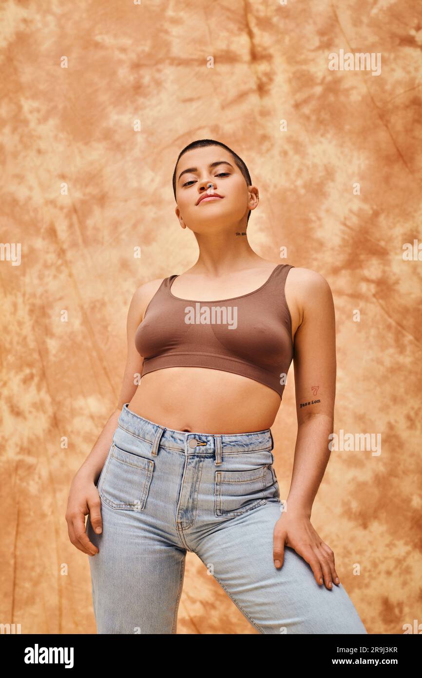 confiance du corps, look jeans, femme ajustée et ajustée en tenue décontractée debout sur fond beige marbré, regardant l'appareil photo, auto-acceptation, gener Banque D'Images